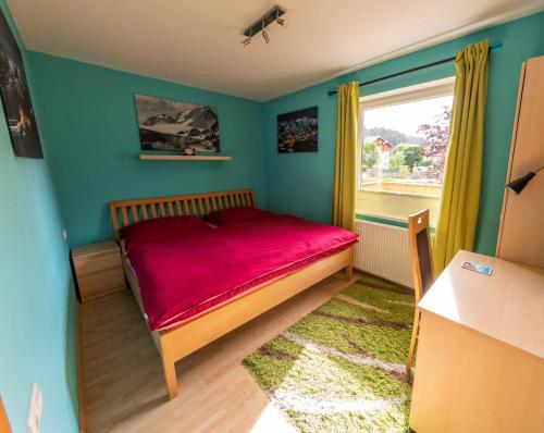 a bedroom with a red bed and a window at Powderia Family & Freelance Apartment in the center of Ski Amadé in Altenmarkt im Pongau