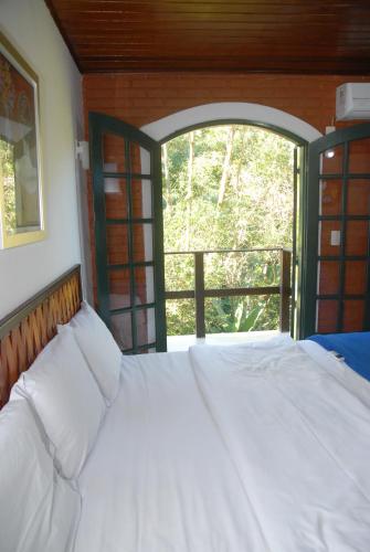 a bed in a room with an open window at Pousada Mirante do Penedo in Penedo