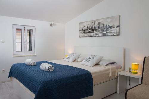 a white bedroom with a bed with a blue blanket at Apartments & Rooms Toni in Split