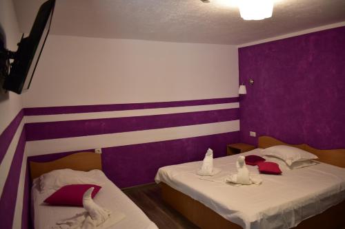 two beds in a room with purple and white walls at Vila Tudor Mamaia Nord in Mamaia Sat/Năvodari