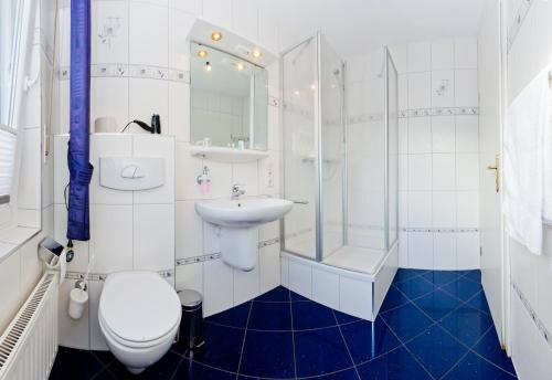 a bathroom with a toilet and a sink and a shower at Kleines Hotel Westhus in Dörpen