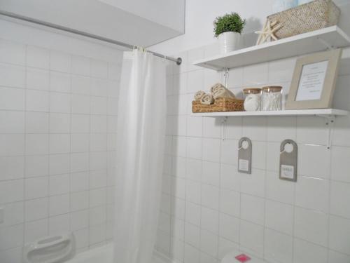 a white tiled bathroom with a shower curtain at Magnolia Apartment in Protaras