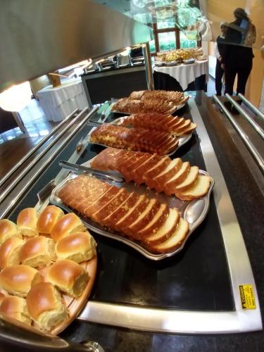 a buffet line with different types of breads and pastries at Satélite - Campos do Jordão in Campos do Jordão