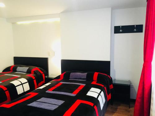 two beds in a room with red curtains at Hotel San José Ipiales in Ipiales