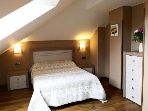 1 dormitorio con 1 cama con colcha blanca en Apartamento Apega, en Ribadeo