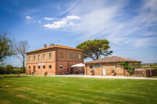 un grand bâtiment en briques avec une pelouse devant lui dans l'établissement Tenuta La Fratta, à Sinalunga