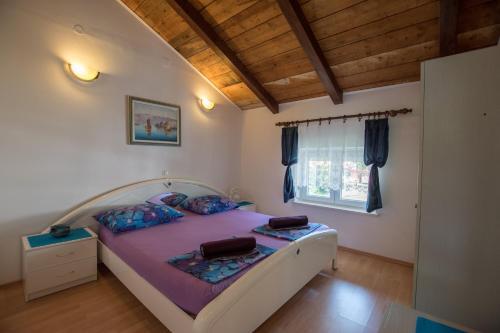 a bedroom with a large bed with purple sheets at Apartments Frkovic in Ledenice