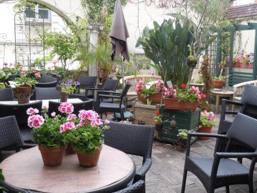 a patio with tables and chairs with flowers and plants at La Croix Blanche in Montrichard