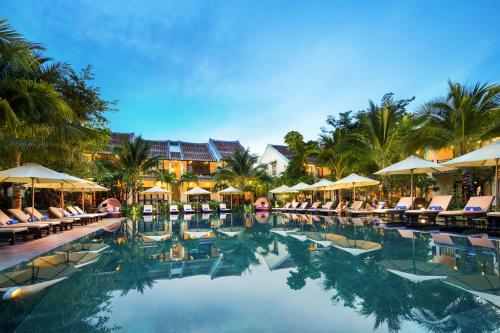 a large swimming pool with chairs and umbrellas at Mulberry Collection Silk Village in Hoi An