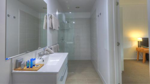 a white bathroom with a sink and a shower at Castaway Norfolk Island in Burnt Pine