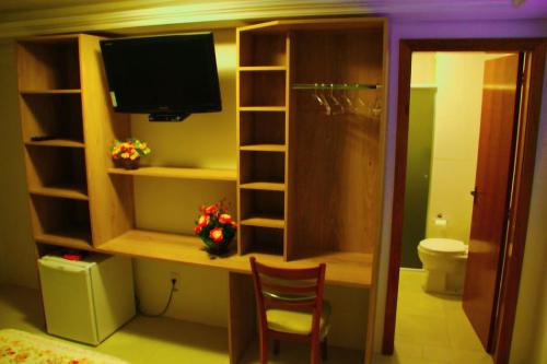 a room with a desk with a television and a toilet at Pousada Florenza in Bento Gonçalves