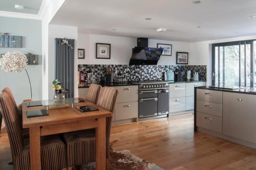 a kitchen with a wooden table with chairs and a stove at Boutique cottage central Wells in Wells