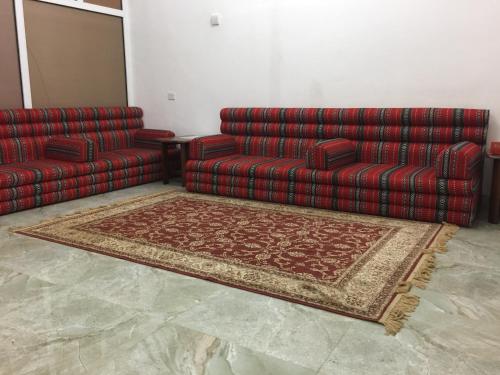 a living room with two couches and a rug at Oriental Nights Rest House in Al Wāşil