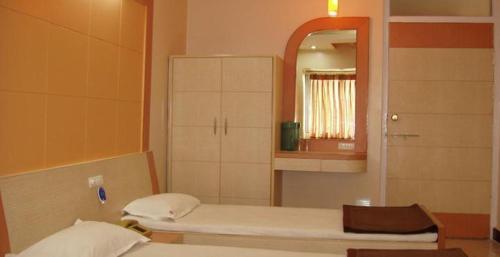 a small room with two beds and a mirror at Hotel Vaishali in Nashik