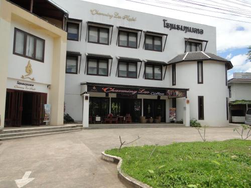 a large white building with a restaurant in front of it at Charming Lao Hotel in Ban Chéng