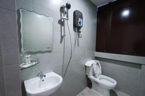 a bathroom with a sink and a toilet and a mirror at Grand FC Hotel in George Town