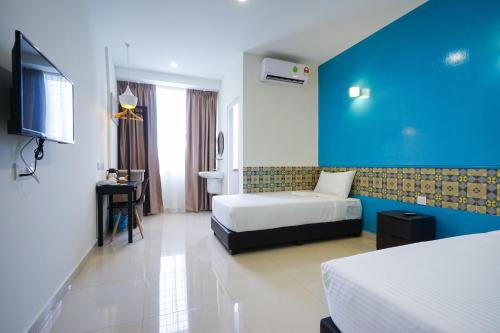 een hotelkamer met 2 bedden en een blauwe muur bij Grand FC Hotel in George Town