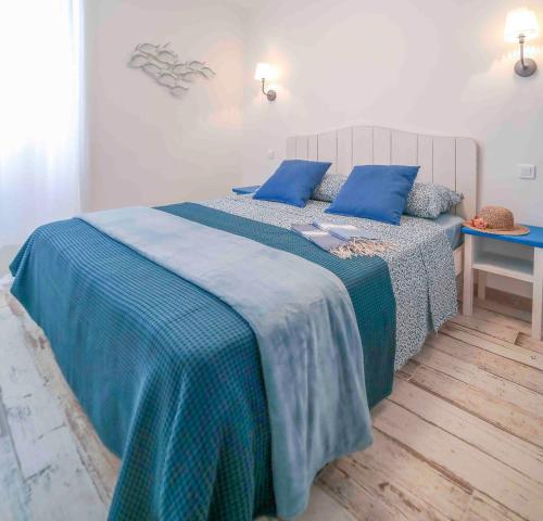una camera da letto con letto con lenzuola blu e cuscini blu di Faro di Capo Testa a Bonifacio