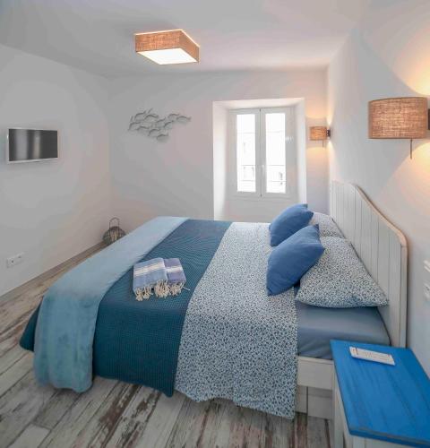 une chambre avec un grand lit avec des oreillers bleus dans l'établissement Faro della Madonetta, à Bonifacio