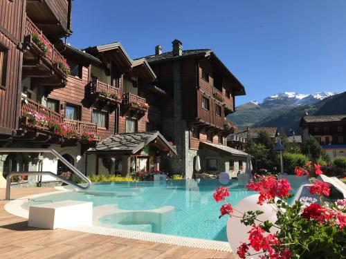 a swimming pool in front of a building with flowers at Hotel Relais Des Glaciers - Adults Only in Champoluc