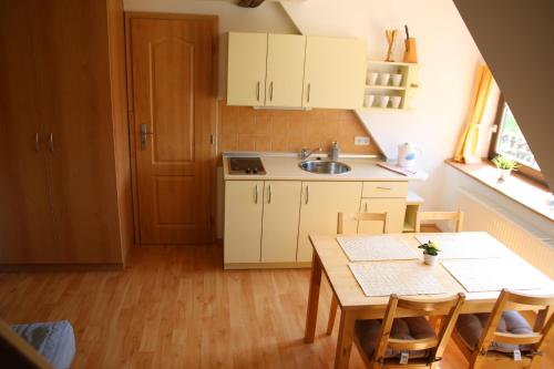 a kitchen with white cabinets and a table and a sink at Apartmány Dolní Moravice in Dolní Moravice