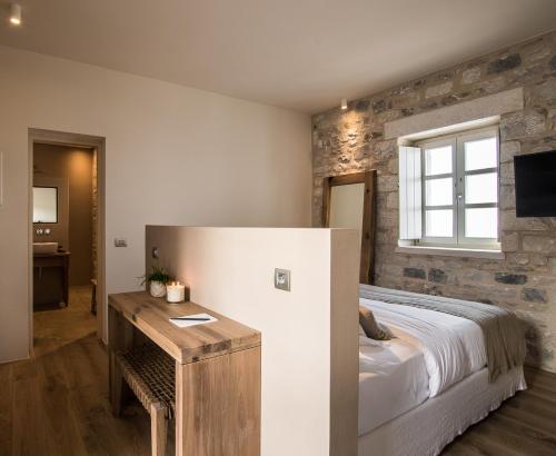 a bedroom with a bed and a wooden table at BASSA MAINA Villas & Suites in Areopolis