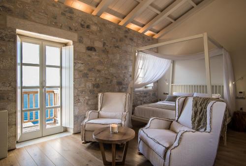 a bedroom with a bed and a couch and a table at BASSA MAINA Villas & Suites in Areopolis