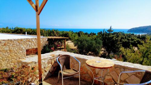 a table and chairs sitting next to a stone wall at Consolas Gavdos Studios in Gavdos