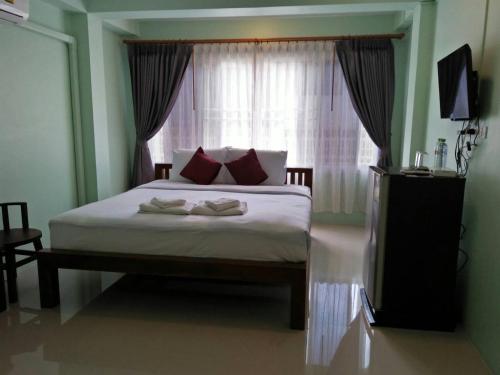 a bedroom with a large bed with a window at Ban Mae Boonthong in Lampang