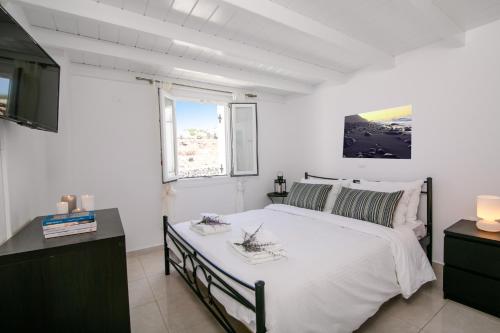 a bedroom with a large bed and a tv at Apanomeria Boutique Residence in Oia