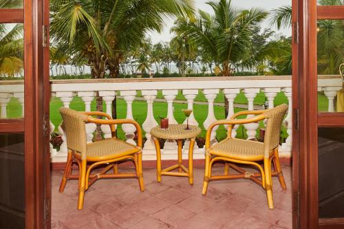a porch with three chairs and a fence at The LaLiT Golf & Spa Resort Goa in Canacona