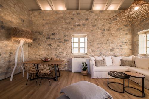 a living room with a white couch and a brick wall at BASSA MAINA Villas & Suites in Areopolis