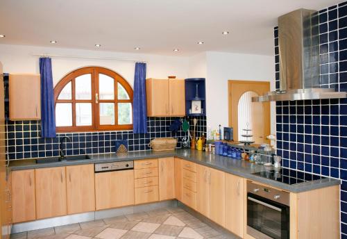 a kitchen with wooden cabinets and blue tiles on the wall at The Pearl of Balaton in Szigliget