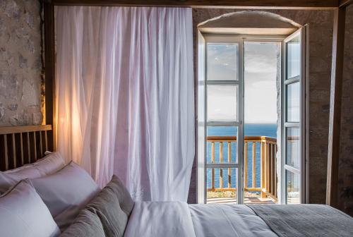 a bedroom with a bed in front of a window at BASSA MAINA Villas & Suites in Areopolis