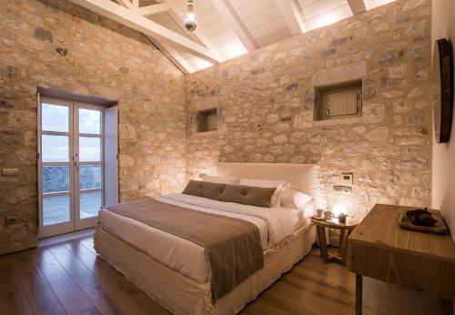 a bedroom with a large bed and a stone wall at BASSA MAINA Villas & Suites in Areopolis