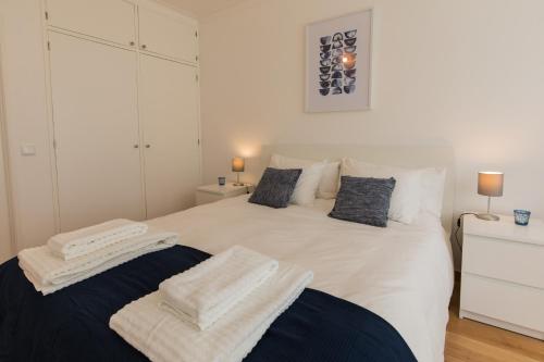 ein Schlafzimmer mit einem weißen Bett und Handtüchern darauf in der Unterkunft "HomeySuite" in Fontainhas in Cascais