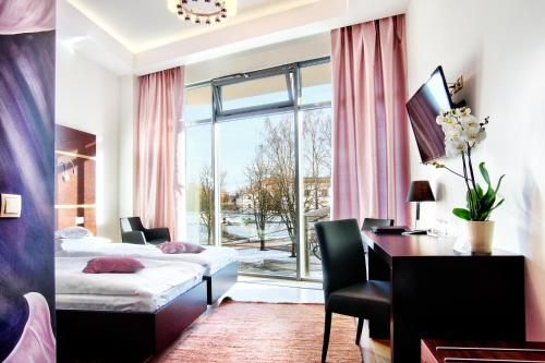 a hotel room with a bed and a desk and a window at BoutiqueHotel Aristo in Białystok