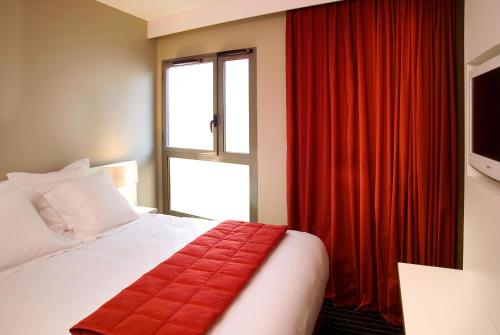 a bedroom with a bed with a red curtain and a window at Résidence Ôtelia Affaires & Bien-être in Lyon
