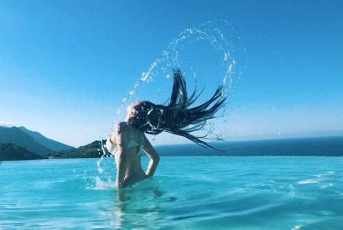 a woman in the water with her hair in the water at Hotel Antica Cascina Del Golfo in Scopello