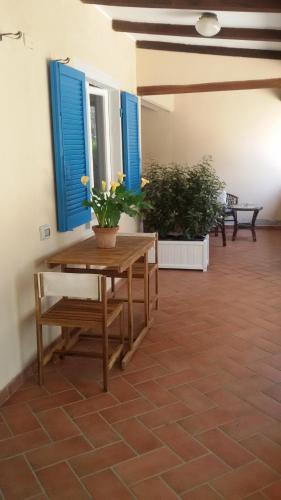 a patio with a wooden table and blue windows at Mirto E Mare in Muravera