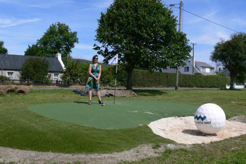 Templeview Lodge في غرينكاسيل: امرأة تقف على وضع أخضر مع كرة غولف