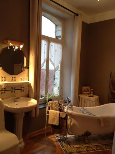 a bathroom with a tub and a sink and a window at Château de Ricquebourg in Maresquel