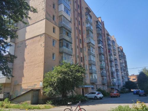 a tall building with cars parked in front of it at Scandinavian Poltava Apartments with 2 rooms, 3 beds 1 sofa in Poltava