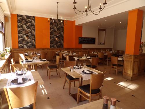 a restaurant with wooden tables and chairs and orange walls at Come Inn in Neufchâtel-en-Bray