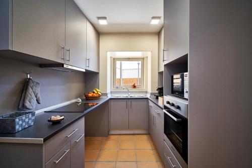 a kitchen with white cabinets and a sink and a window at Up Estalagem dos Padres in Albergaria-a-Velha