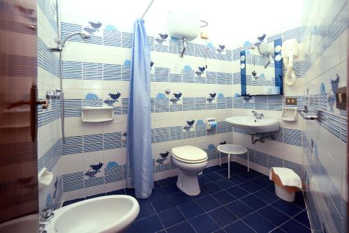 a blue and white bathroom with a toilet and sink at Hotel Timiama in Peschici