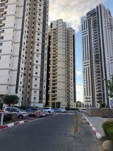 eine Stadt mit hohen Gebäuden und Autos, die auf einer Straße geparkt sind in der Unterkunft Apartment "Style City" With Sea View in Bat Yam