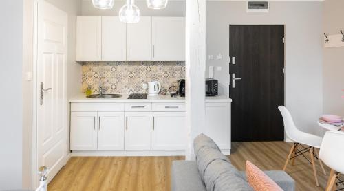 a kitchen with white cabinets and a gray couch at Apartament na Wierchu in Bukowina Tatrzańska