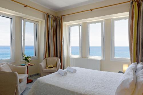 a bedroom with a bed and windows with the ocean at Sea Breeze Apartments Chios in Monolia