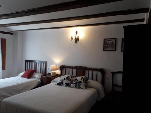 a bedroom with two beds and a light on the wall at Fonda Del Tozal in Teruel